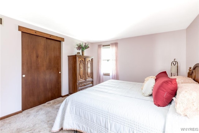 bedroom with a closet, baseboards, visible vents, and light carpet
