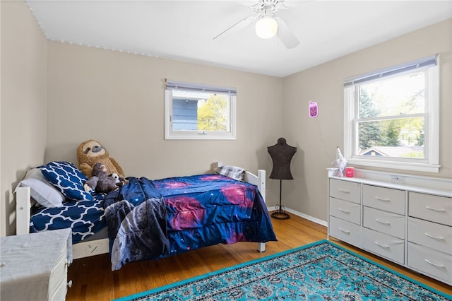bedroom featuring baseboards, ceiling fan, multiple windows, and wood finished floors