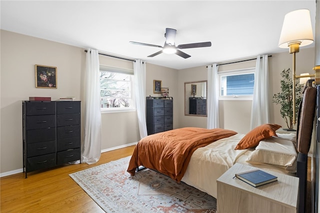 bedroom with baseboards, a ceiling fan, and light wood-style flooring