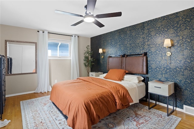 bedroom with baseboards, ceiling fan, wood finished floors, and visible vents