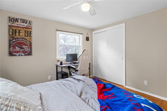 bedroom with a ceiling fan, baseboards, wood finished floors, and a closet