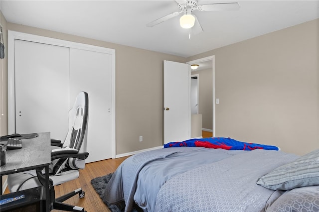 bedroom with baseboards, ceiling fan, wood finished floors, and a closet