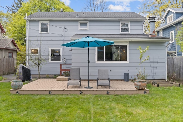 back of property featuring fence, a yard, and a wooden deck