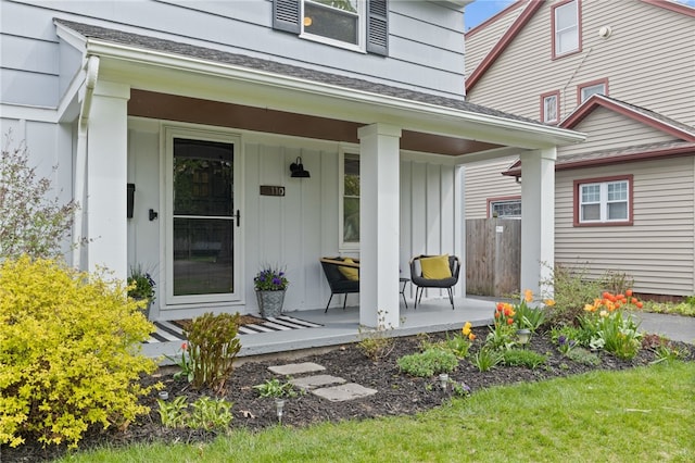 doorway to property featuring board and batten siding, roof with shingles, and covered porch