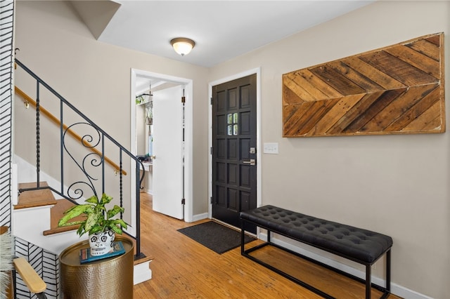 entryway with baseboards, stairs, and light wood finished floors