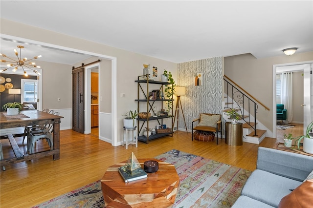 living area with a barn door, wood finished floors, and stairway