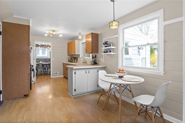 kitchen featuring a sink, light countertops, a chandelier, light wood-style flooring, and visible vents
