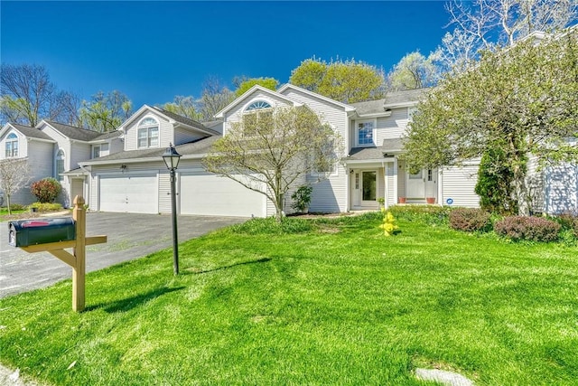 townhome / multi-family property with an attached garage, a shingled roof, a front yard, and aphalt driveway