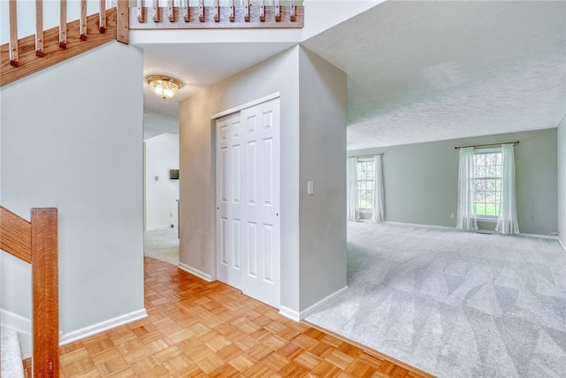 carpeted entrance foyer featuring baseboards and a textured ceiling
