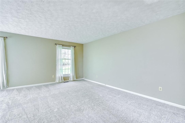carpeted spare room with baseboards and a textured ceiling