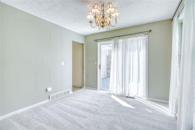 carpeted spare room featuring baseboards, a textured ceiling, visible vents, and an inviting chandelier