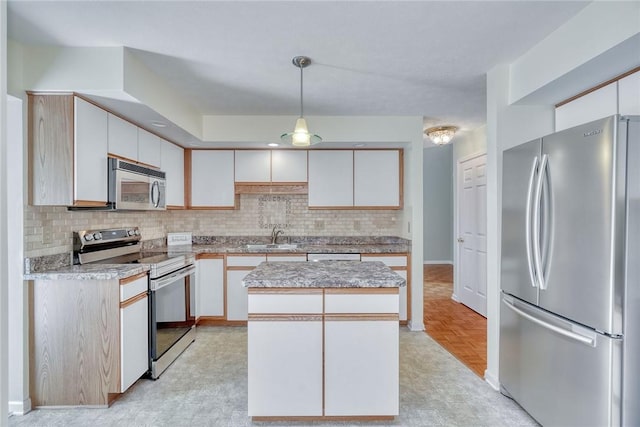 kitchen featuring a center island, light countertops, backsplash, hanging light fixtures, and stainless steel appliances