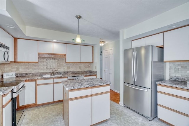 kitchen with a kitchen island, tasteful backsplash, a sink, stainless steel appliances, and white cabinetry