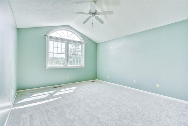 unfurnished room featuring visible vents, lofted ceiling, carpet flooring, baseboards, and a ceiling fan