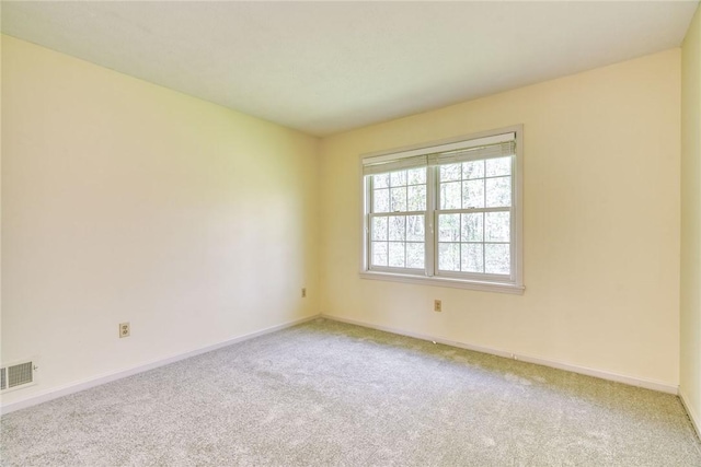 unfurnished room with baseboards, visible vents, and light carpet