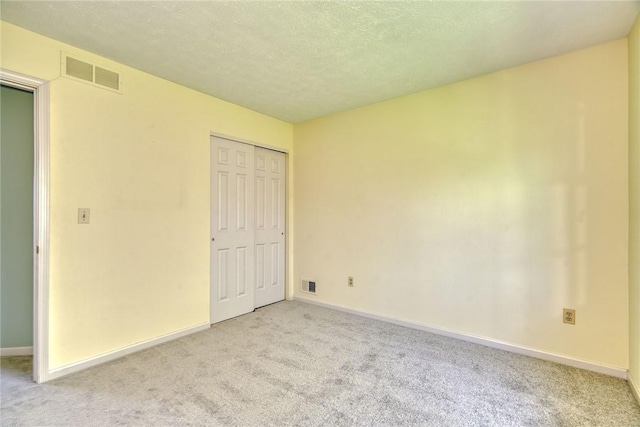 unfurnished bedroom featuring visible vents, carpet, baseboards, and a closet