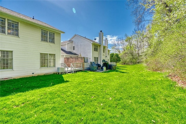 rear view of house with a lawn and a wooden deck
