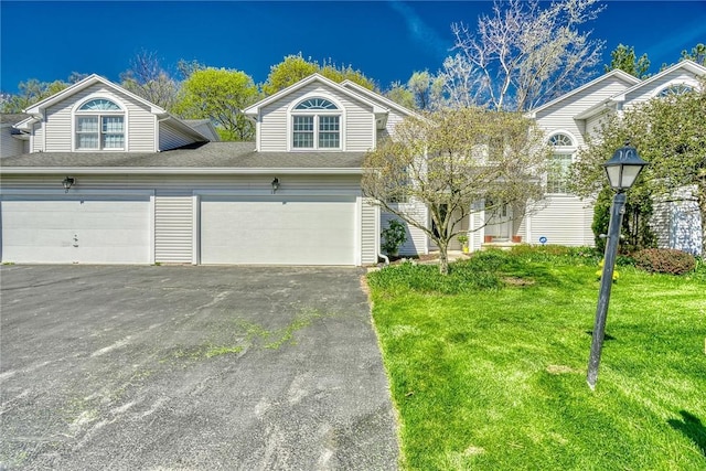 multi unit property featuring an attached garage, a front lawn, and aphalt driveway