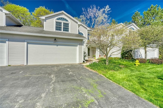 view of front of house featuring a shingled roof, an attached garage, a front lawn, and aphalt driveway