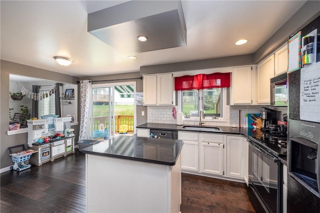 kitchen with a sink, dark countertops, black appliances, and white cabinetry