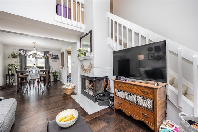 living area featuring stairway, a fireplace, wood finished floors, and a chandelier