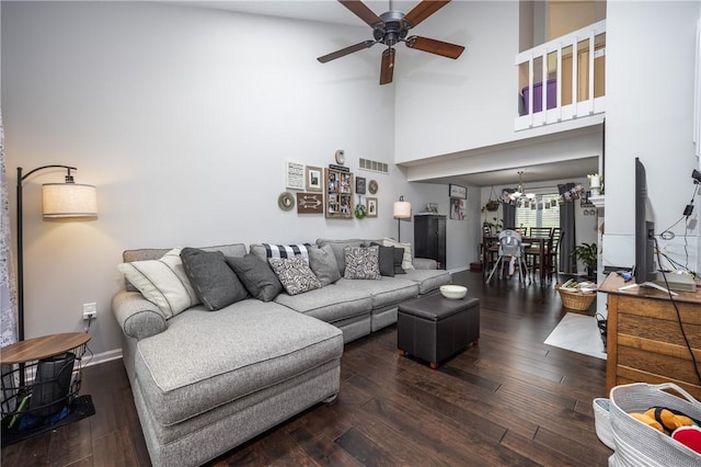 living area with a high ceiling, ceiling fan with notable chandelier, baseboards, wood finished floors, and visible vents