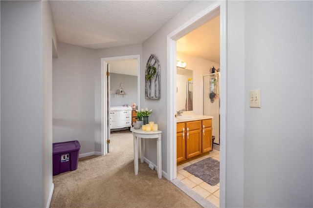 hallway featuring a textured ceiling, light colored carpet, and a sink