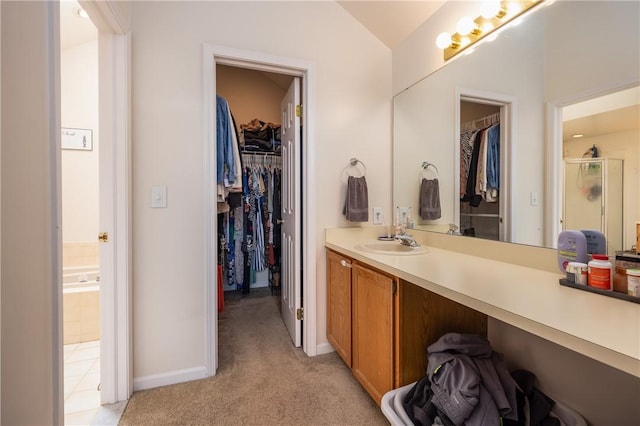 full bath with vanity, baseboards, lofted ceiling, a spacious closet, and a stall shower