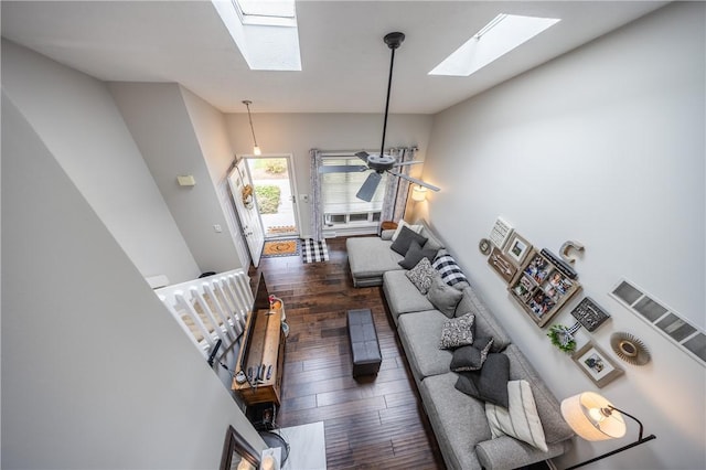 living area with wood-type flooring, a ceiling fan, and vaulted ceiling with skylight