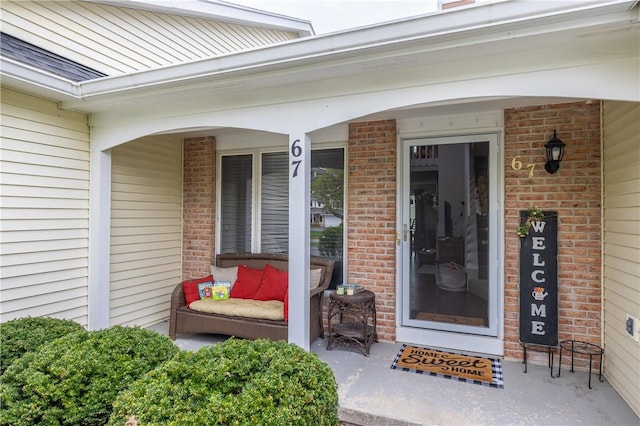 view of exterior entry with a porch and brick siding