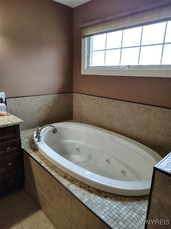 full bath featuring a jetted tub, vanity, and tile patterned flooring