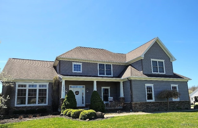 view of front of house with a shingled roof and a front lawn