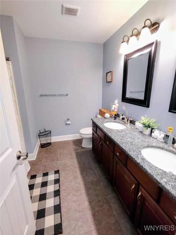 bathroom with toilet, tile patterned floors, visible vents, and a sink