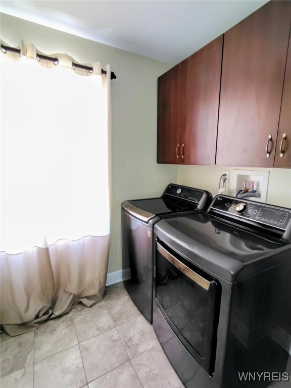laundry area with cabinet space, light tile patterned floors, baseboards, and washer and clothes dryer