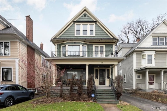 american foursquare style home featuring covered porch and a balcony