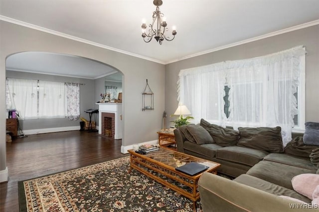living area featuring an inviting chandelier, ornamental molding, wood finished floors, baseboards, and arched walkways
