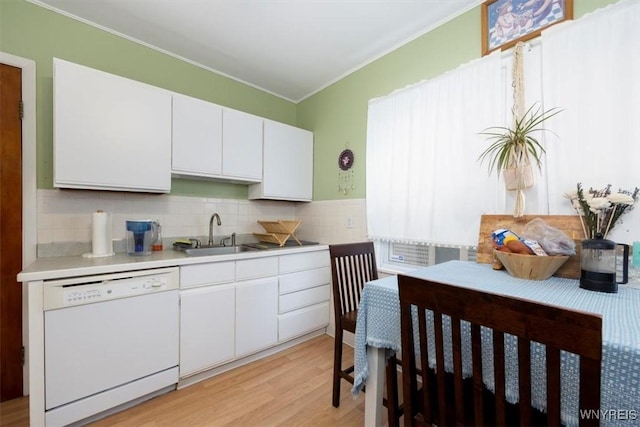 kitchen with crown molding, light countertops, a sink, light wood-style flooring, and dishwasher