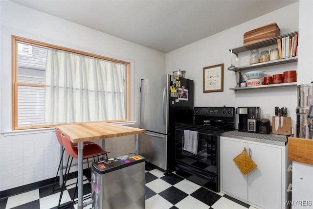 kitchen with freestanding refrigerator, tile patterned floors, black electric range oven, and open shelves