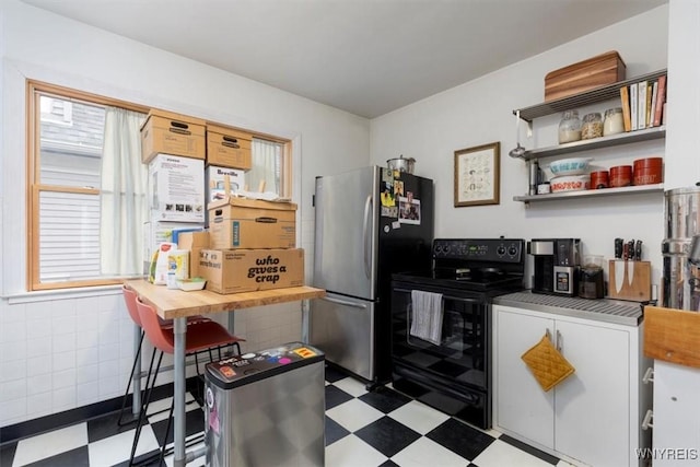 kitchen featuring freestanding refrigerator, electric range, tile patterned floors, and plenty of natural light