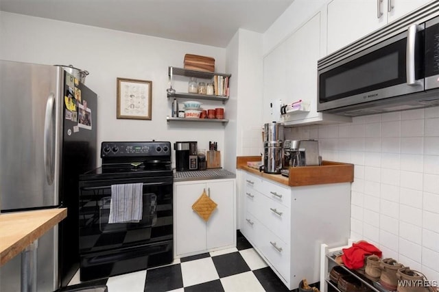 kitchen featuring dark floors, white cabinets, stainless steel appliances, and butcher block countertops