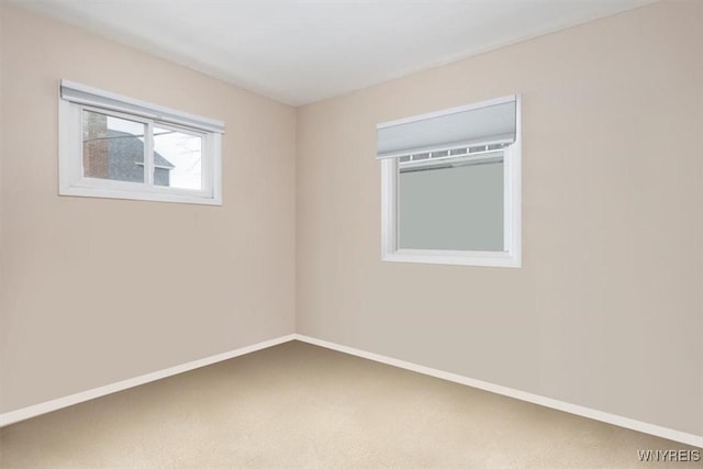 carpeted empty room featuring baseboards