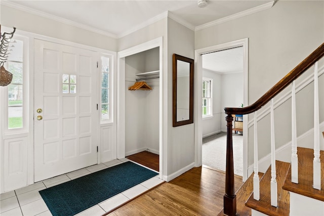entryway featuring baseboards, ornamental molding, wood finished floors, and stairway