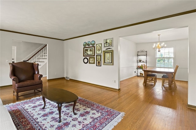 living room featuring crown molding, baseboards, a chandelier, and wood finished floors