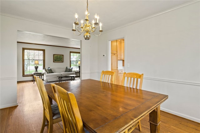 dining space with an inviting chandelier, baseboards, crown molding, and light wood-style floors