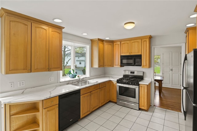 kitchen featuring open shelves, light stone counters, a sink, light tile patterned floors, and black appliances