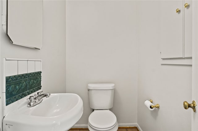 bathroom with toilet, baseboards, and a sink