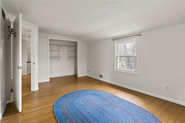 unfurnished bedroom featuring a closet, lofted ceiling, and wood finished floors
