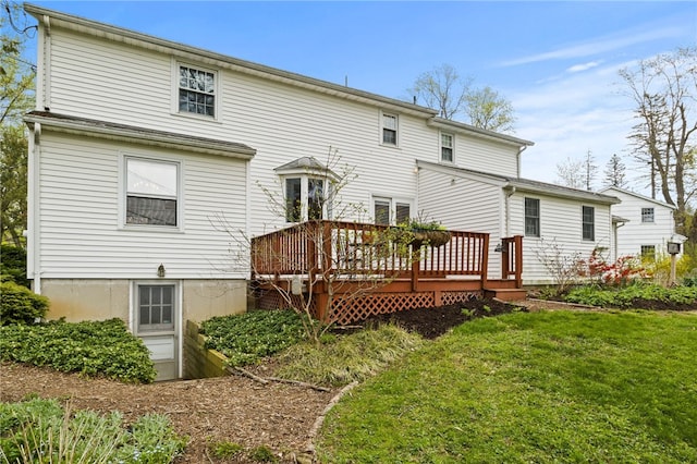 rear view of house featuring a wooden deck and a yard