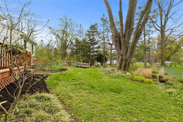 view of yard featuring fence, a wooden deck, and a garden