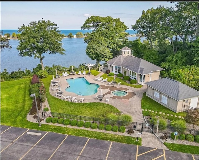pool featuring a lawn, a water view, a patio area, and fence private yard